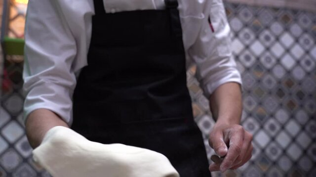Cook tossing and rolling out the dough, selective focus