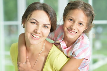 Portrait of a charming little girl hugging with mom at home