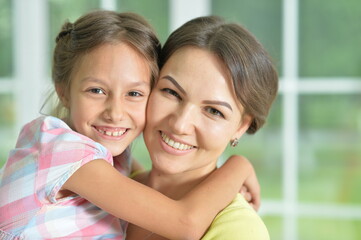 Portrait of a charming little girl hugging with mom at home