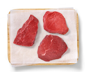 Raw steak in a studio setting, on a wooden plank