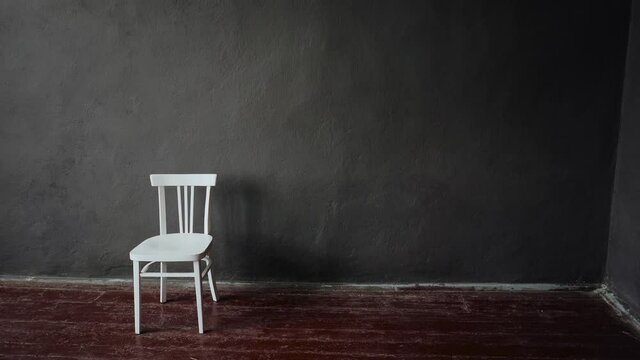 The white chair stands in an empty room with brown floors and gray walls