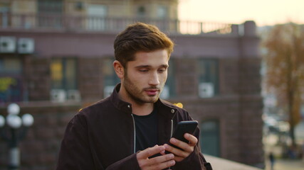 Euphoric guy receiving message phone outdoors. Excited man gesturing like winner