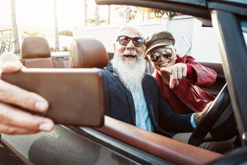 Happy senior couple taking selfie on new convertible car - Mature people having fun in cabriolet...