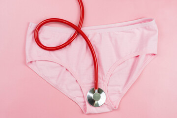 Fototapeta premium Pink underpants and red stethoscope isolated on pink background.Woman hygiene, Concept of sanitary pad,critical days, menstruation,health care