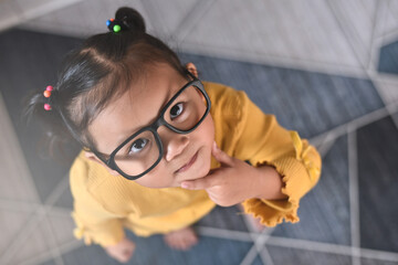 smart little asian girl with thinking gesture looking at camera. concept of child education