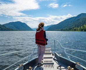 Young woman on a boat on Teletskoe lake in Altai