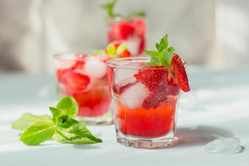 Glasses of strawberry soda drink on light blue background. Summer healthy detox lemonade, cocktail or another drink background. Nonalcoholic drinks, super food, vegetarian or healthy diet concept.