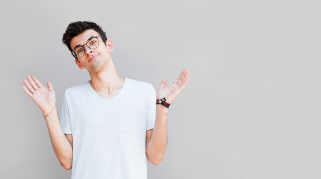 Closeup portrait of dumb clueless young man, arms out asking what's the problem who cares so what, I don't know. Isolated on white background. Negative human emotion, facial expressions, attitude