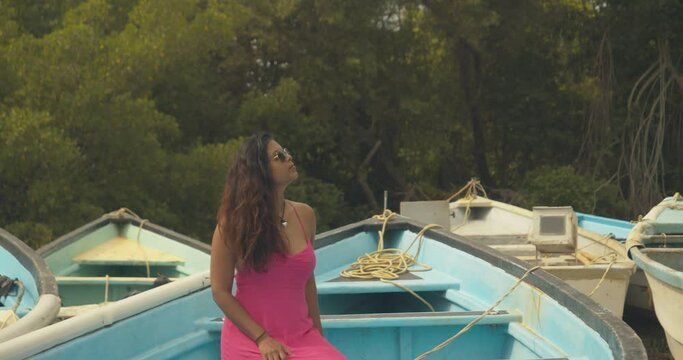 A model looks in the trees of this mangrove while sitting in a fishing boat