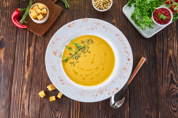 Organic vegan pumpkin creme soup on wood table with ingredients, healthy diet food concept, top view