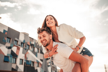 Ragazza bella e attraente sorride giocando sulle spalle del suo uomo mentre sono in giro durante...