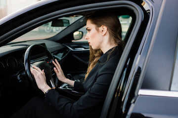 Fototapeta na wymiar Young businesswoman in black wear with a expensive car