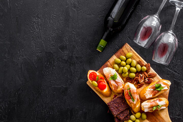 Wine appetizer. Toasts, nuts, olives on black desk top view copy space