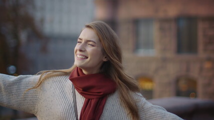 Excited woman dancing outdoors. Cheerful hipster girl whirling on street.