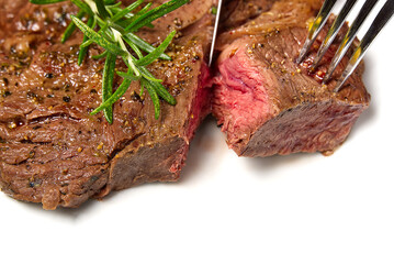 Medium rear beef steak. White plate with Piece of beef steak on fork.