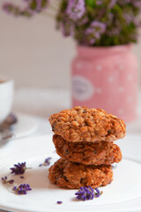 Oatmeal cookies on a saucer decorated with lavender flowers, tea and thyme bouquet