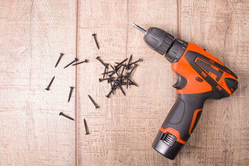 black wood screws black screwdriver on a brown wooden background