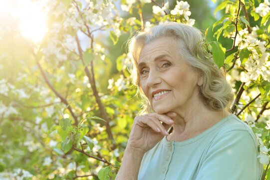 Portrait of beautiful senior woman posing near blooming tree