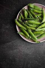 Home grown fresh green peas on beautiful pink plate with copyspace