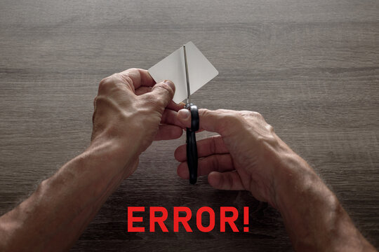 male hands with scissors cut the payment card. concept of liquidation, destruction of deactivation, decommissioning with the inscription error.