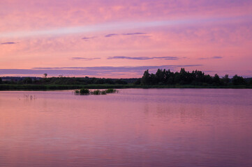 Fototapeta na wymiar Beautiful pink vibrant sunset on a forest lake