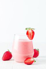 A glass of fresh strawberry smoothie on a wooden background. Summer drink shake, milkshake, juice and refreshment organic concept.
