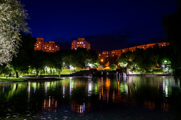 Naklejka premium Night city park with a river and beautiful lanterns in summer