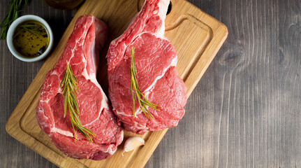 Raw fresh meat, beef and pork steak, ribeye, with rosemary, pepper and salt. Marbled beef cutlet with salt and spices.