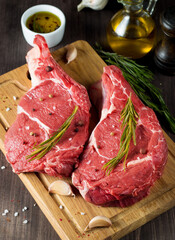 Raw fresh meat, beef and pork steak, ribeye, with rosemary, pepper and salt. Marbled beef cutlet with salt and spices.