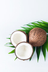Fototapeta na wymiar Ripe half cut coconut with green leaves on a white background. Isolated concept.