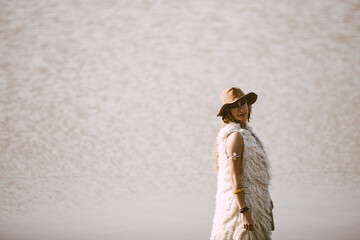 A blonde bohemian woman with a hat outdoors in a lake background
