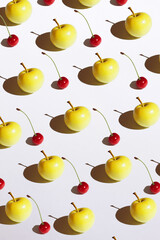 Yellow apple and cherry minimalism pattern with hard shadow on the white background isolated. Top view flat lay, copy space.