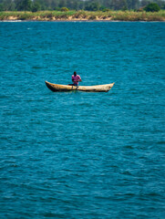 Unrecognizable fisherman fishing over wooden canoe, lake Malawi