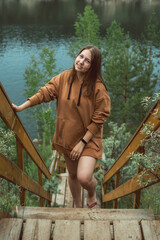smiling carefree woman in hoody posing on beautiful nature view with lake, enjoying beautiful scenery and relaxing. people in nature and calmness concept. Camping