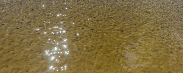 Glare of the sun and waves at the bottom of the river