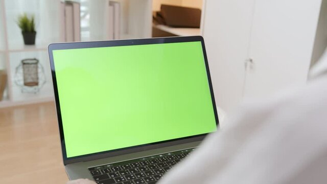 handle shot of woman using laptop with looking at green screen.