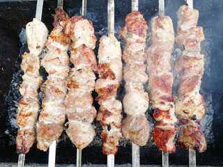 pork shish kebab on skewers is fried on coals in the grill. Top view, flat lay, picnic, unhealthy food