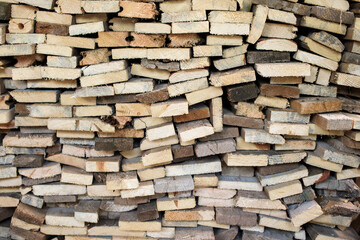 A large pile of cut wooden boards arranged along a wall