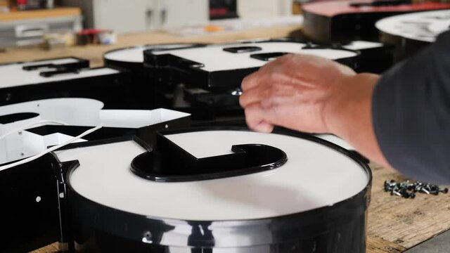 Man is using screwdriver as he works with signage. Close up video as man&rsquo;s hands are working with the signage.
