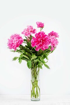 a bouquet of peony flowers in a glass vase on a white background