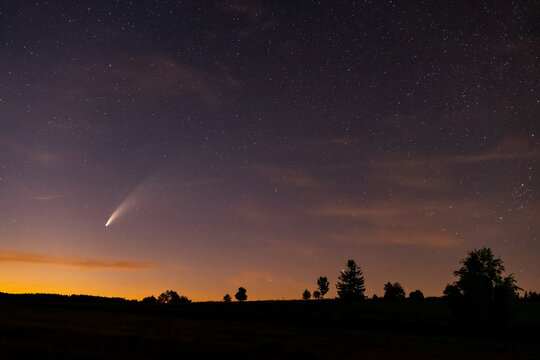 Comet Neowise (C/2020 F3) with the colorful starry sky and silhouette of the hill with trees