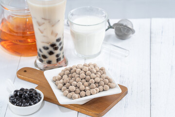 Bubble milk tea with tapioca pearl topping ingredient, famous Taiwanese drink on white wooden table background in drinking glass, close up, copy space