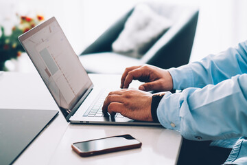 Fototapeta premium Closeup of businessman hands in blue shirt keyboarding email text message on modern pc computer at home interior table. Male work online via banking on laptop netbook. Office workspace with netbook