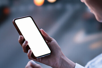 Woman's hands holding mobile phone with lighted big copy space touch screen outdoors with evening bokeh light of city. Close up view of female person using smartphone app for online shopping