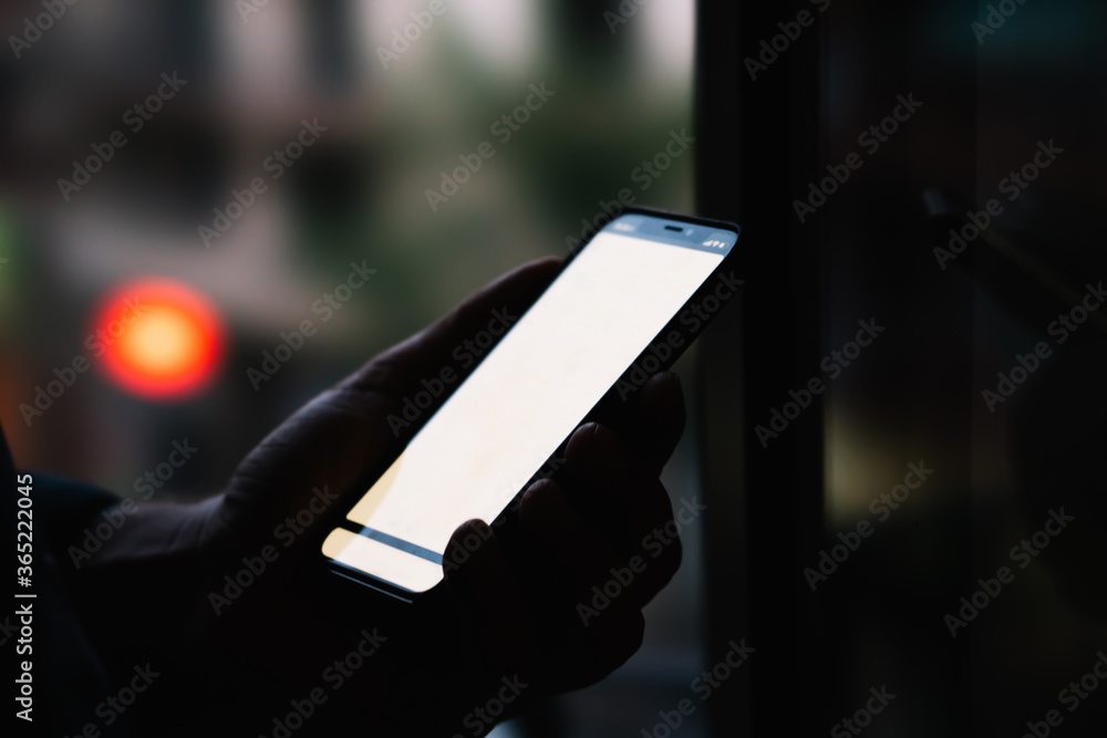 Poster side close up view of male person holding modern smartphone with mock up copy space screen while sta