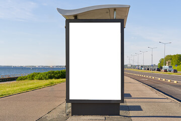 glass bus stop by the sea, with a white advertising space. Blank billboard and outdoor advertising....