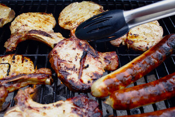 Grillfleisch wird mit einer Grillzange gedreht
