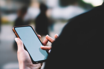 Cropped view of female finger typing text information on display of digital smartphone and choosing ap on website to install.Woman's hands holding mobile phone and making payment online using internet