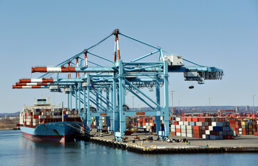 Newark, NJ / USA - View of the container terminal with berthed ship, gantry cranes are loading and...