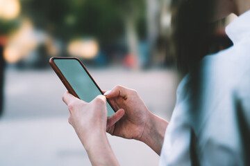 Cropped view of hipster blogger messaging in chat on modern smartphone with mock up area.Female hands holding cellular and typing information on digital device using 4G internet connection